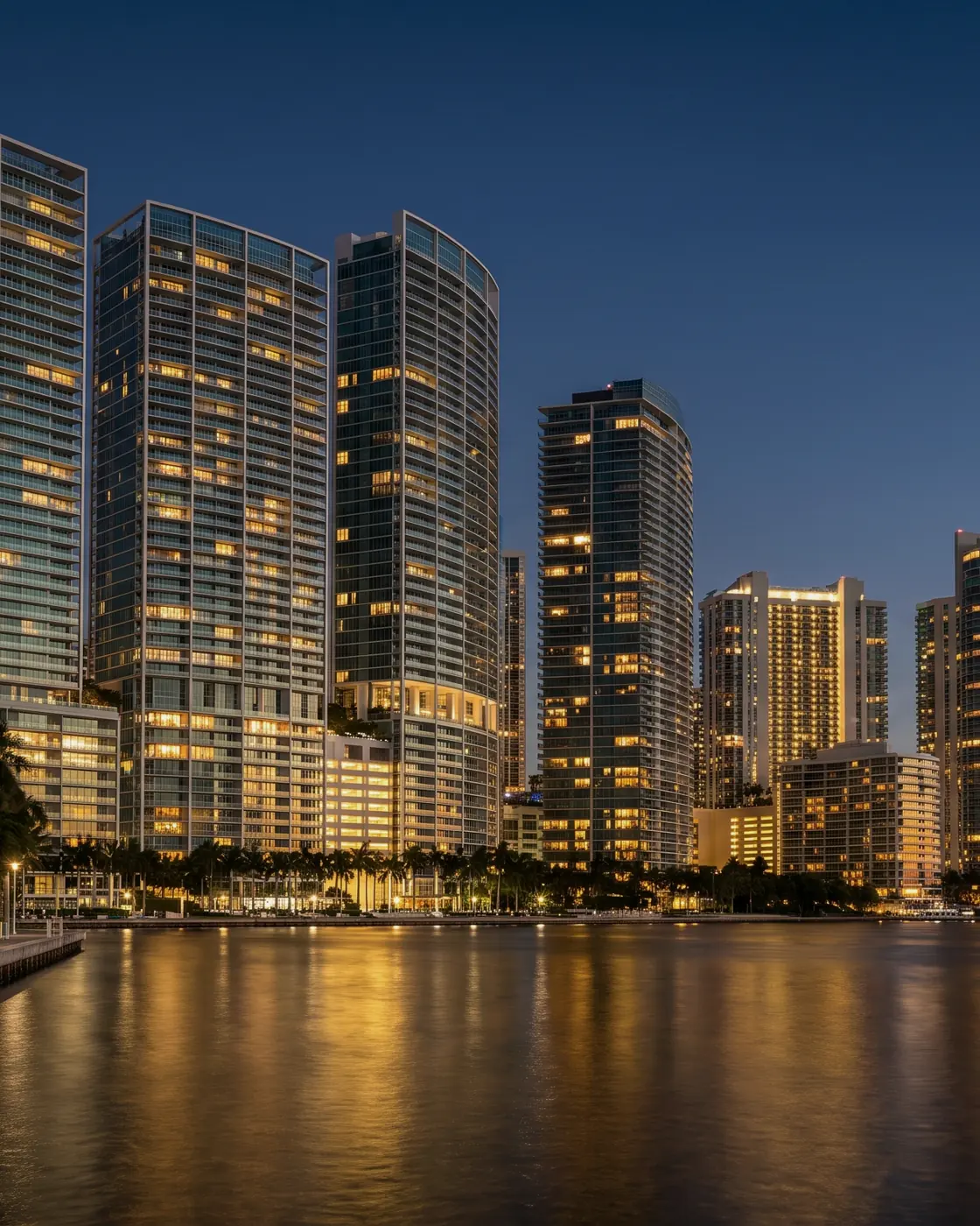 Torres de condominios de vidrio junto a la bahía al anochecer